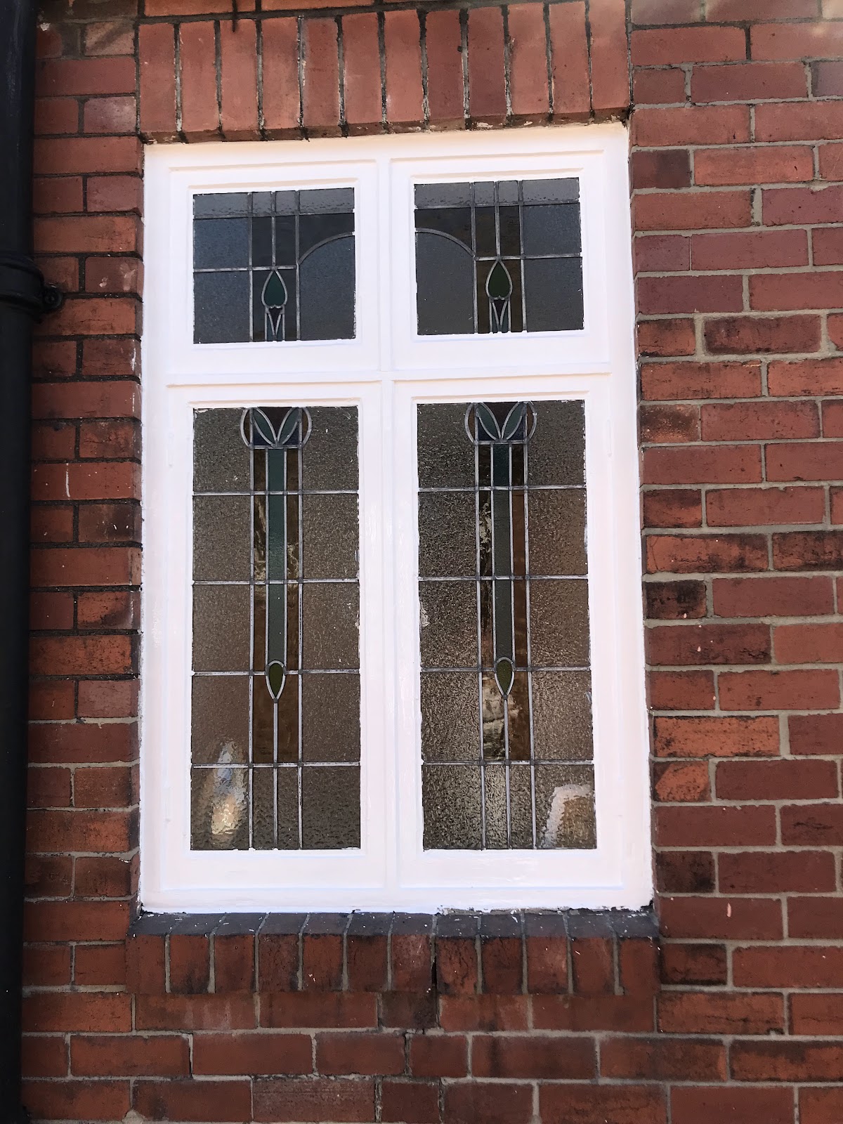 Original leaded window with freshly glossed white frame against red brick