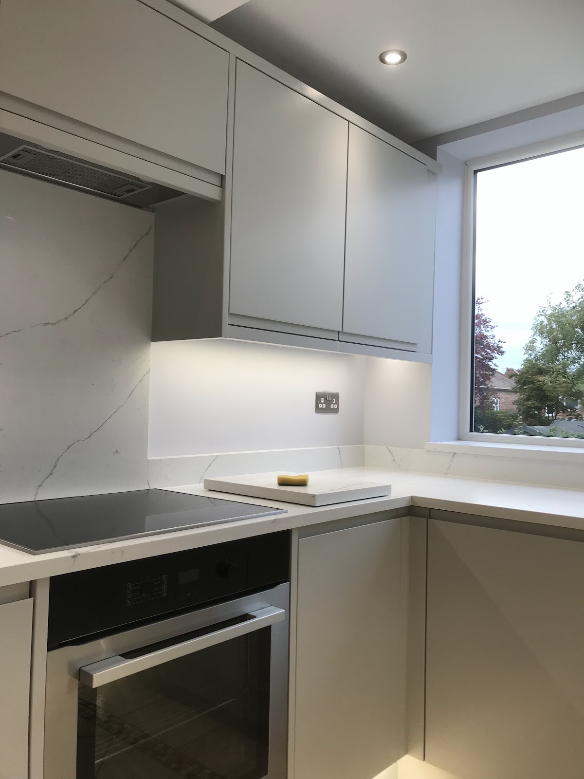 Kitchen decorated in pale grey with marble effect worktop and splashback