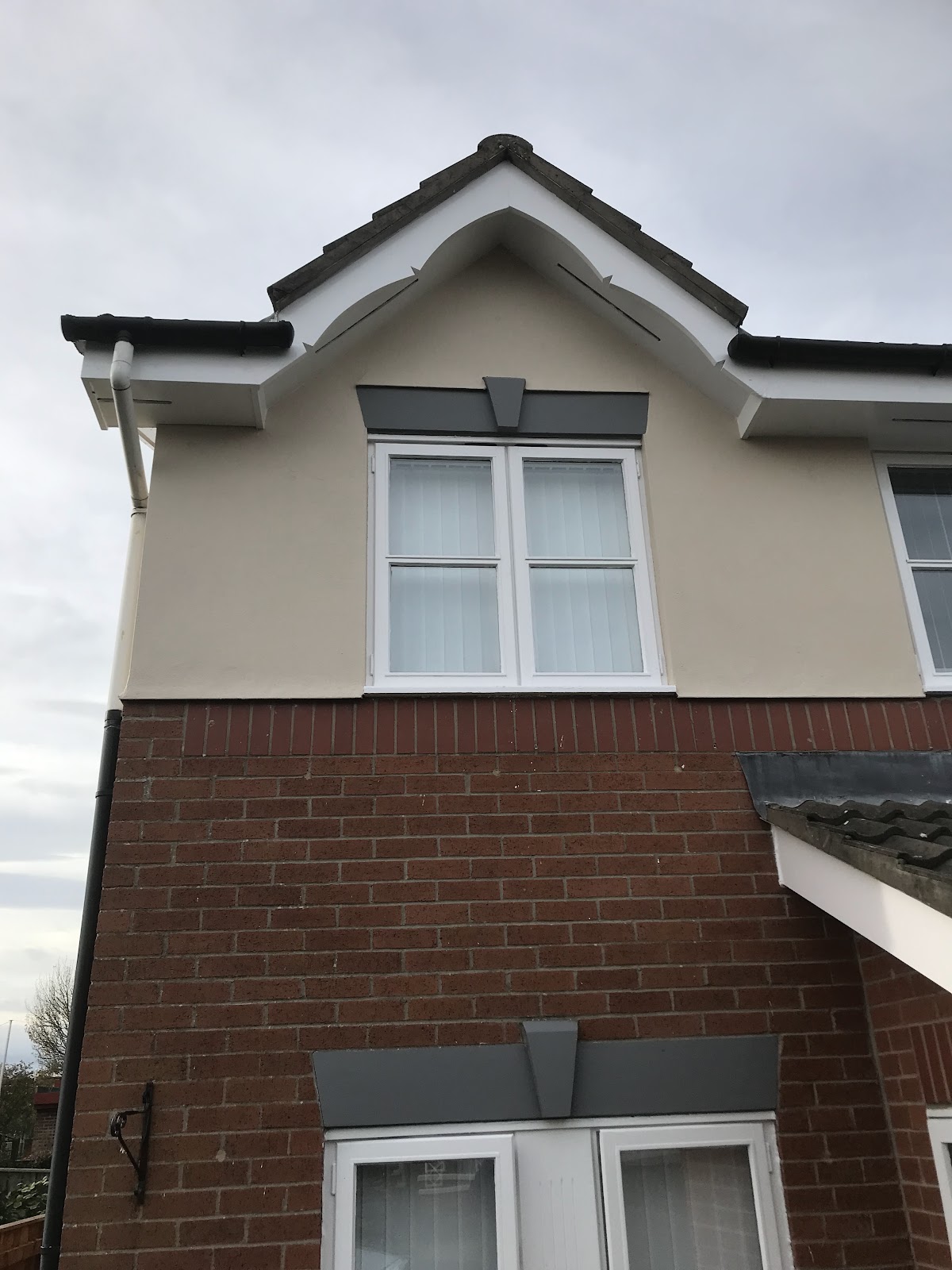 Exterior gable painted in cream render with white fascias and grey lintels