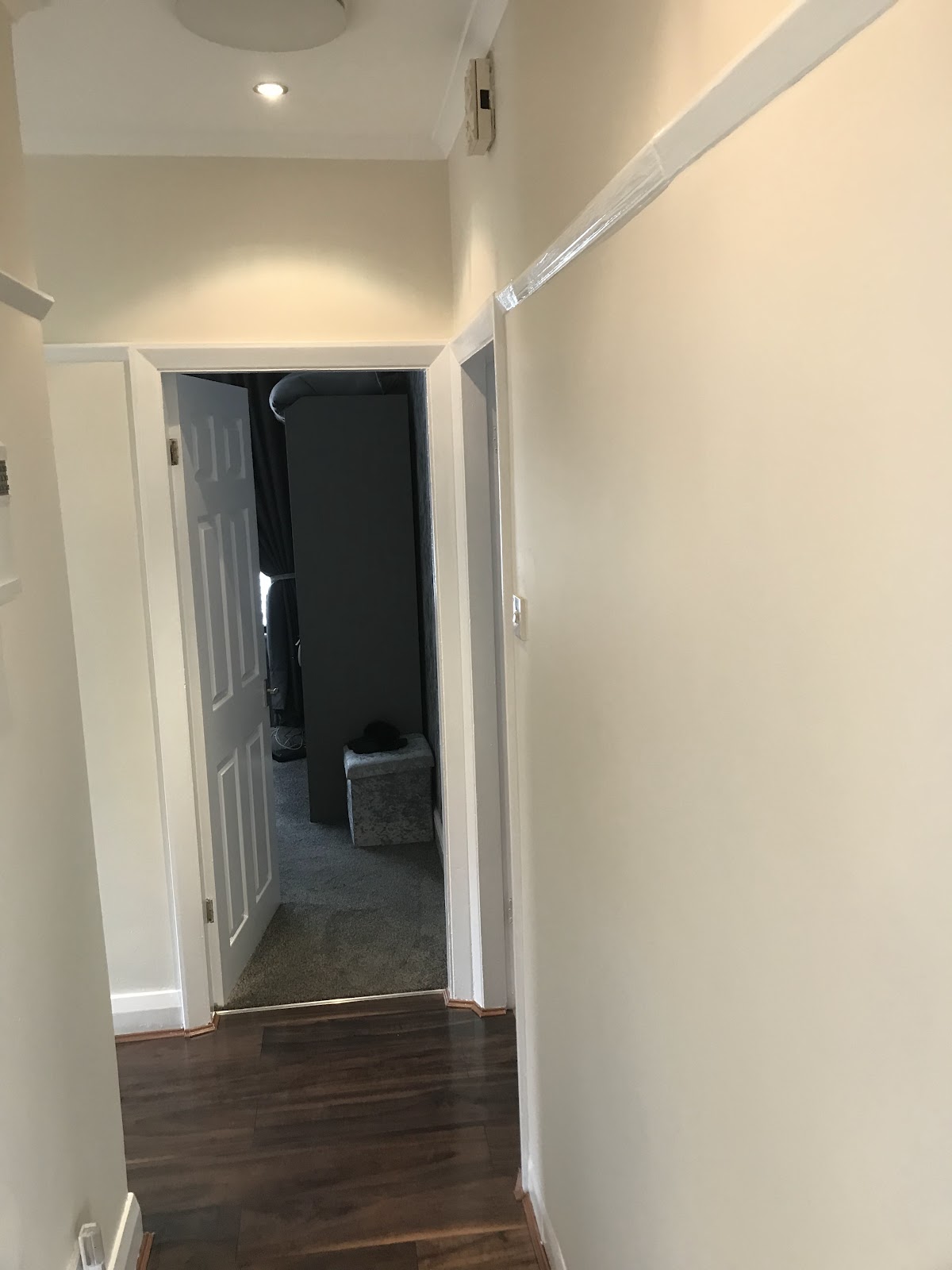 Hallway decorated in cream with white woodwork and dark wood flooring